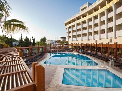 Área de piscina del hotel con tumbonas y habitaciones con balcón bajo el sol