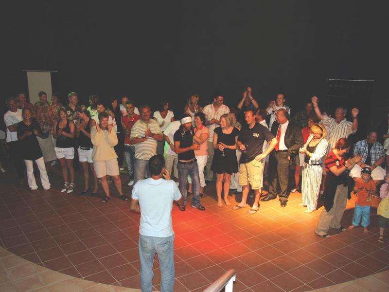 Personas se reúnen en un patio por la noche mientras una persona habla al frente.