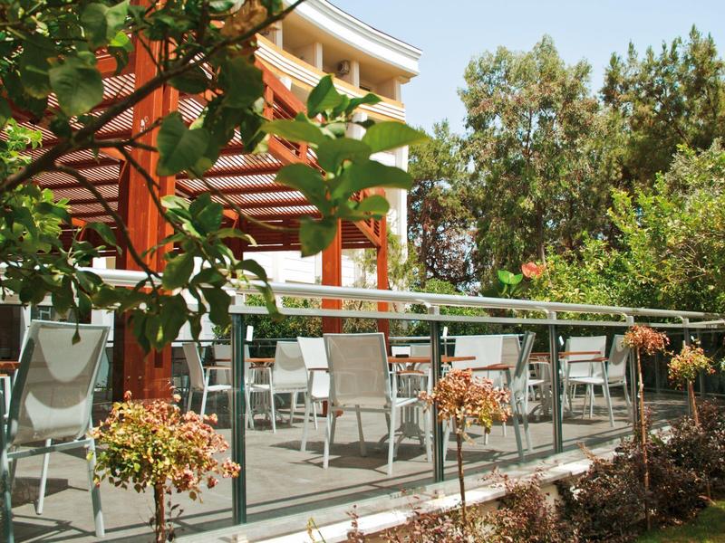 Terraza con sillas blancas y flores frente a un edificio moderno del hotel.