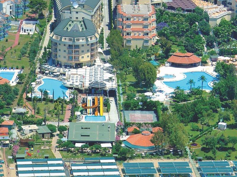 Vista aérea de un gran hotel con varias piscinas y acceso directo a una playa de arena.