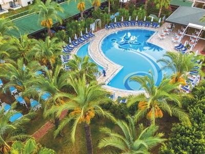 Basen hotelowy w tropikalnym otoczeniu z leżakami i bujną zielenią.