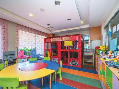 Kolorowy pokój zabaw dla dzieci z jasnymi stołami, krzesłami i domkiem strażackim.