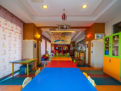 Kolorowy pokój zabaw dla dzieci z małymi stołami, krzesłami i żywą wykładziną.