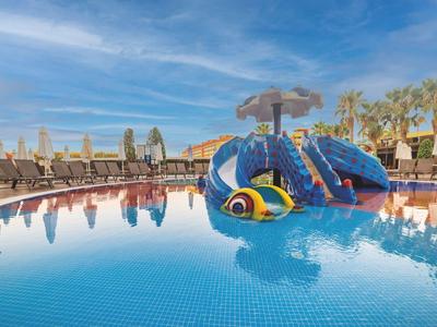 Dziecięca zjeżdżalnia w kształcie węża w hotelowym basenie pod słonecznym niebem