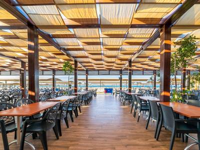 Jasna, nowoczesna restauracja z drewnianą podłogą i dużymi oknami z widokiem na jezioro.