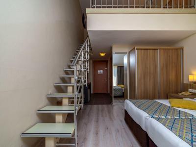 Nowoczesny pokój hotelowy ze schodami na antresolę, łóżkiem podwójnym i drewnianą szafą.