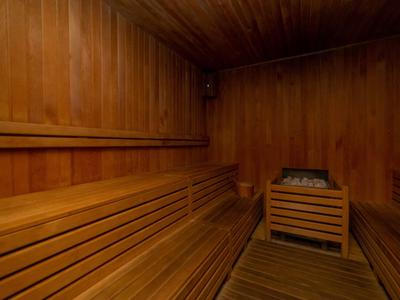 Drewniana sauna z ławkami i piecem z kamieniami w hotelu