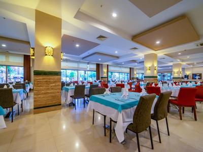 Przestronna, jasna sala jadalna z nakrytymi stołami i krzesłami w kolorach czerwonym, brązowym i niebieskim.