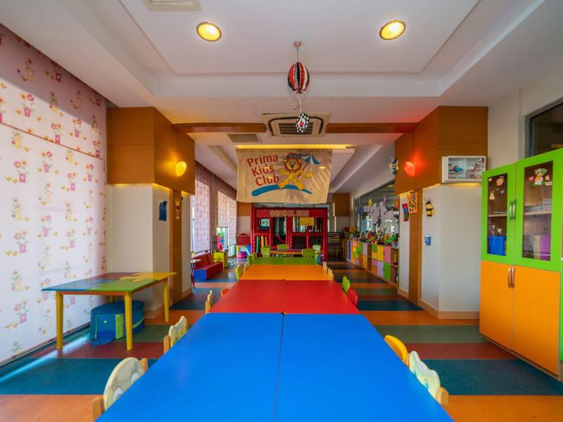 Kolorowy pokój zabaw dla dzieci z małymi stołami, krzesłami i żywą wykładziną.