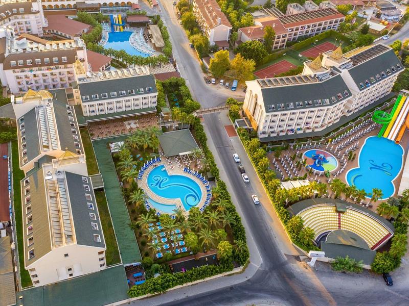 Zdjęcie z lotu ptaka hotelu z kilkoma basenami, zielonymi ogrodami i przyległymi drogami.