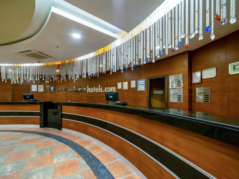 Nowoczesna lobby hotelowa z zakrzywioną recepcją i wiszącymi dekoracjami na suficie.