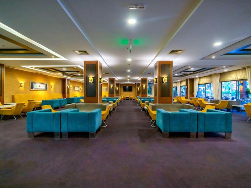 Duża hotelowa lobby z niebieskimi i żółtymi siedzeniami oraz nowoczesnym oświetleniem.