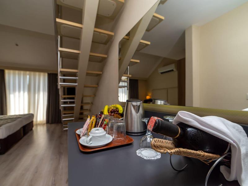 Pokój hotelowy ze schodami, sofą, łóżkiem i tacą z winem oraz szklankami na pierwszym planie.