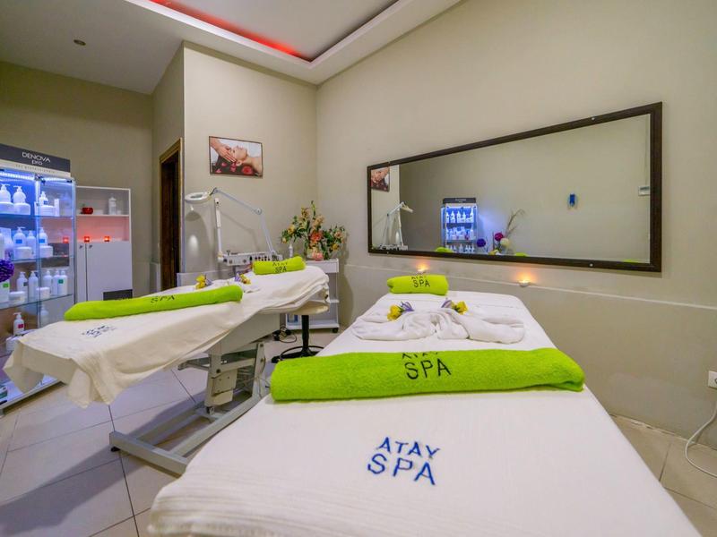 Jasno oświetlony pokój spa z dwoma łóżkami do zabiegów i dużymi lustrami.