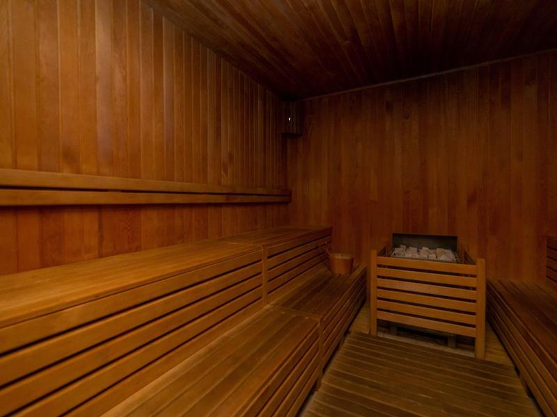 Drewniana sauna z ławkami i piecem z kamieniami w hotelu