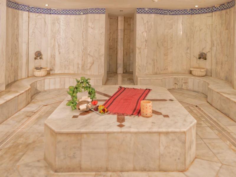 Intérieur d'un hammam turc traditionnel avec fontaine en marbre et serviettes rouges.