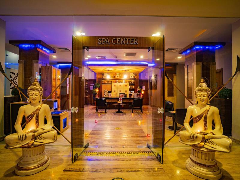 Entrée d'un spa avec deux statues de Bouddha assises et éclairage chaleureux.