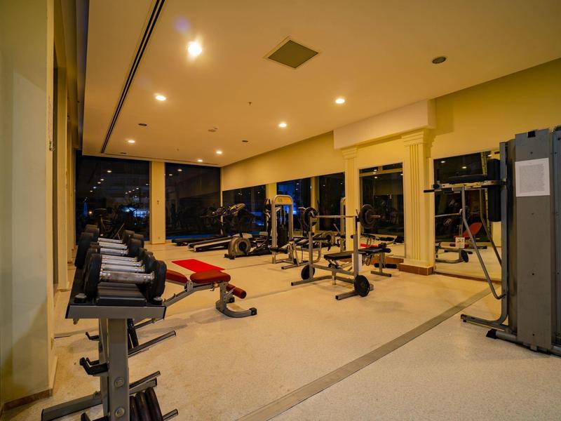 Salle de sport moderne avec divers équipements d'entraînement et grandes fenêtres dans un hôtel.