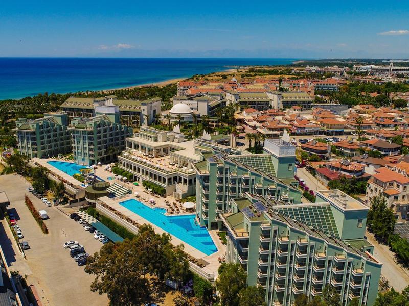Vue aérienne d'un complexe avec de longues piscines, des hôtels et la mer bleue en arrière-plan.