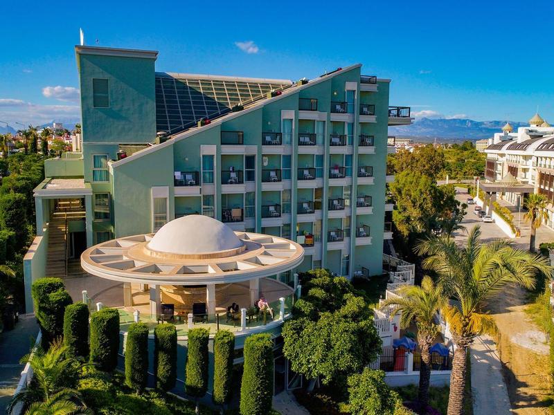 Hôtel moderne avec architecture unique et palmiers environnants sous un ciel ensoleillé.