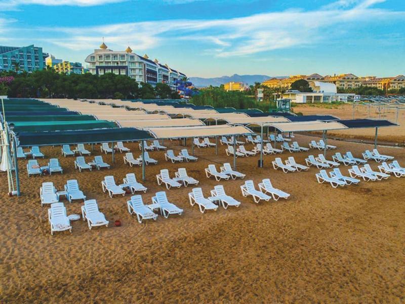 Chaises longues vides et parasols sur la plage de sable devant des hôtels au coucher du soleil.