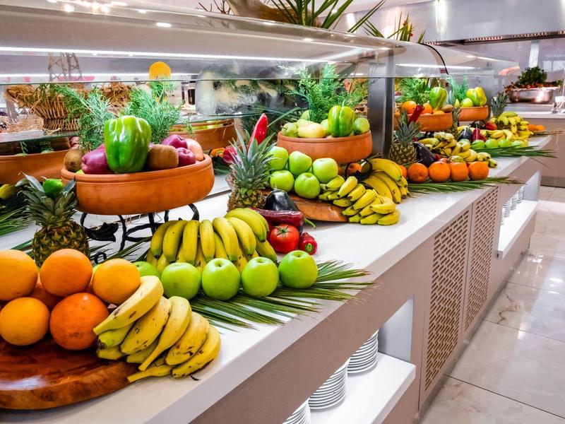 Buffet coloré avec une variété de fruits frais dans une salle à manger d'hôtel lumineuse.