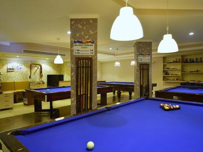 Wnętrze pokoju rekreacyjnego z kilkoma stołami do bilarda i nowoczesnym oświetleniem.