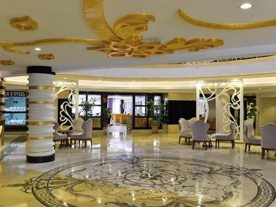 Przestronna lobby hotelowa z ozdobną marmurową podłogą i eleganckimi meblami.