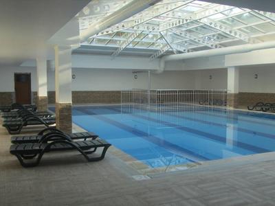 Vnitřní bazén s lehátky a velkými skleněnými okny ve střeše