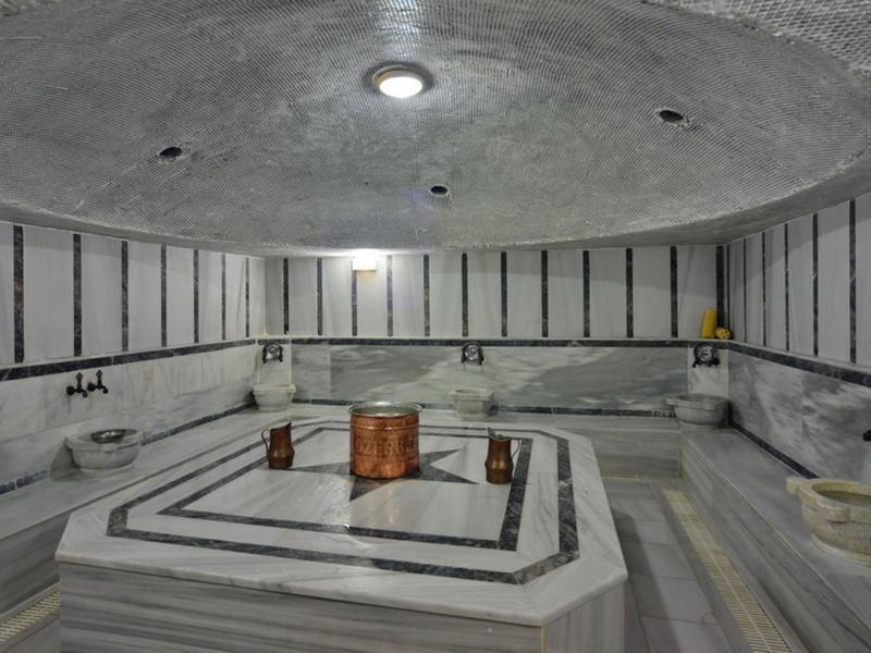 Tradiční turecké hammam s centrální mramorovou umyvadlem a sezením podél stěn.
