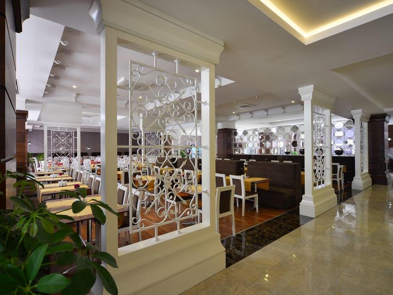 Elegantní, moderní restaurace hotelu s bílými přepážkami a stylovým nábytkem.