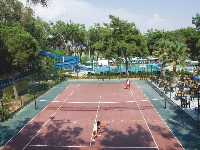 Zastřešená venkovní restaurace s bílými ubrusy na stolech a výhledem na bazén.