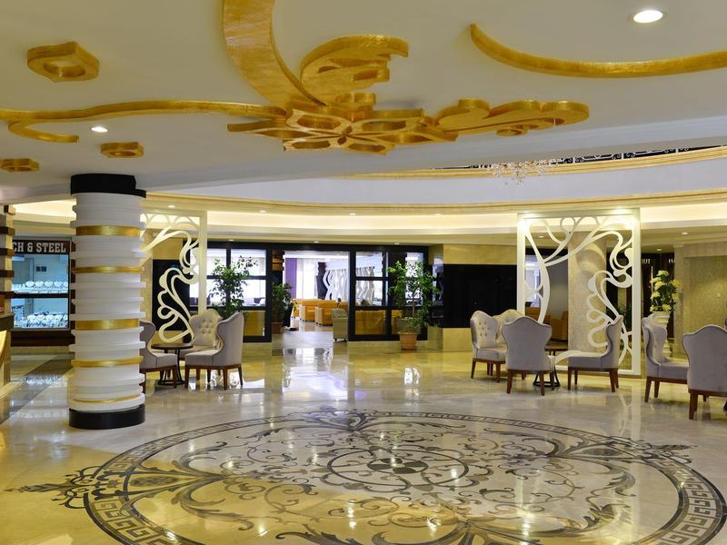 Prostorná hotelová lobby s ozdobnou mramorovou podlahou, pohodlnými křesly a dekorativními sloupy.