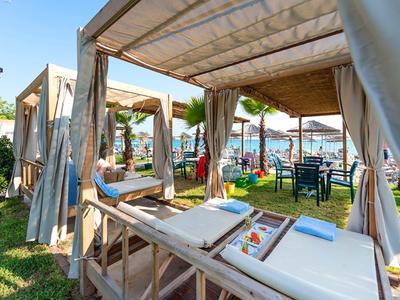 Outdoor cabanas with massage tables and a view of the beach and sea in a sunny resort.