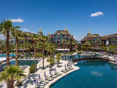 Resort di lusso con grande piscina, palme e lettini sotto un cielo azzurro terso.