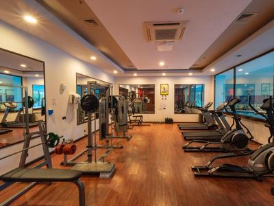 Moderner Fitnessraum mit Holzboden, Cardio- und Kraftgeräten und großen Fenstern.