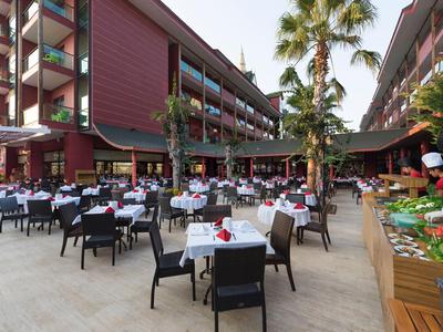 Großer Außenbereich eines Hotels mit zahlreichen gedeckten Tischen und Palmen.