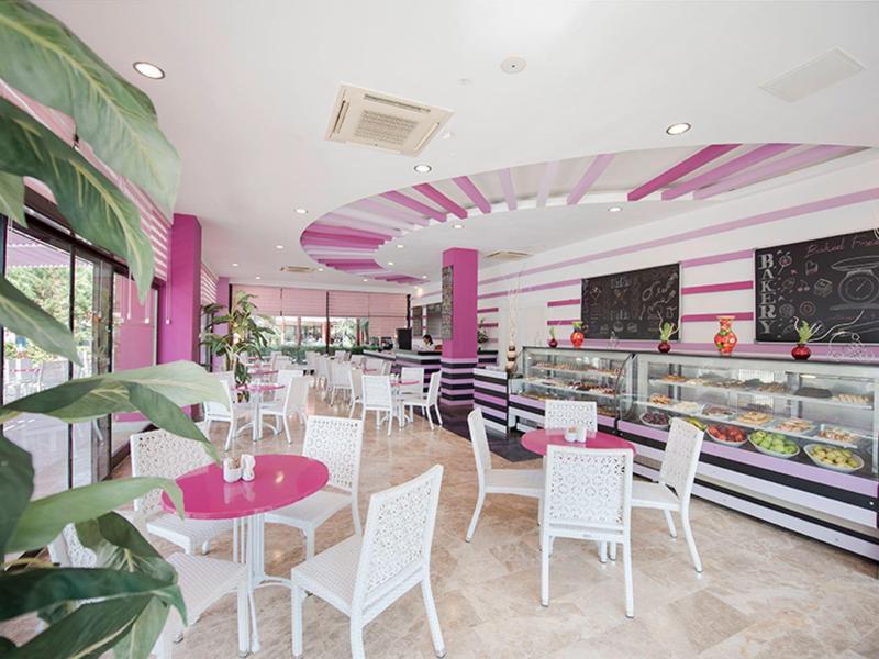 Bright cafe interior with pink and white decor, striped counter, and large windows.