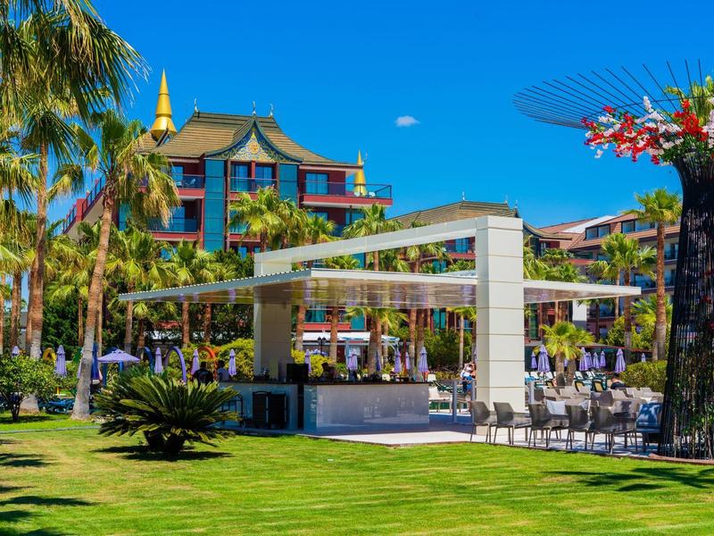 Outdoor bar and seating area surrounded by palm trees and tropical plants at a resort.
