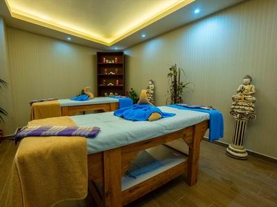 Cozy spa room with two massage tables, folded towels, and soft ambient lighting.