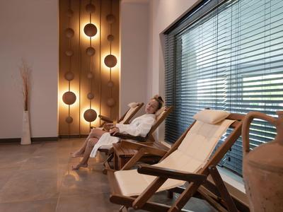 Uvolněná osoba ležící na lehátku v moderní wellness zóně s nepřímým osvětlením.