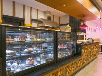 Moderne Hotelbar mit beleuchtetem Glasvitrinenschrank voller Kuchen und Gebäck.