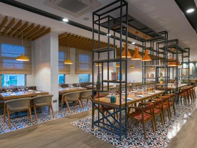 Modernes Restaurant mit langer Bartheke, Holzstühlen und dekorativen Pendelleuchten.