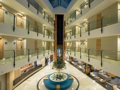 Hell beleuchteter Hotellobby mit moderner Einrichtung und mehreren Etagen.