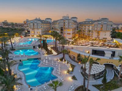 Luxuriöses Hotel mit beleuchtetem Poolbereich und gepflegten Wegen bei Sonnenuntergang.