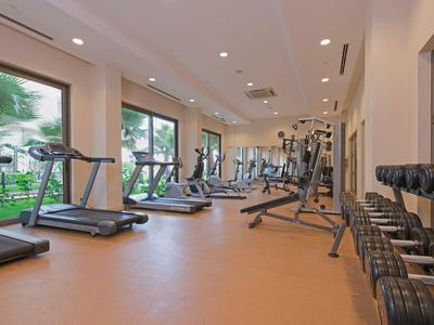 Modern ausgestatteter Fitnessraum mit Laufbändern und Hanteln, Große Fenster mit Gartenblick