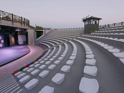 Leeres, halbkreisförmiges Amphitheater mit weißen Sitzkissen und Holzgeländer