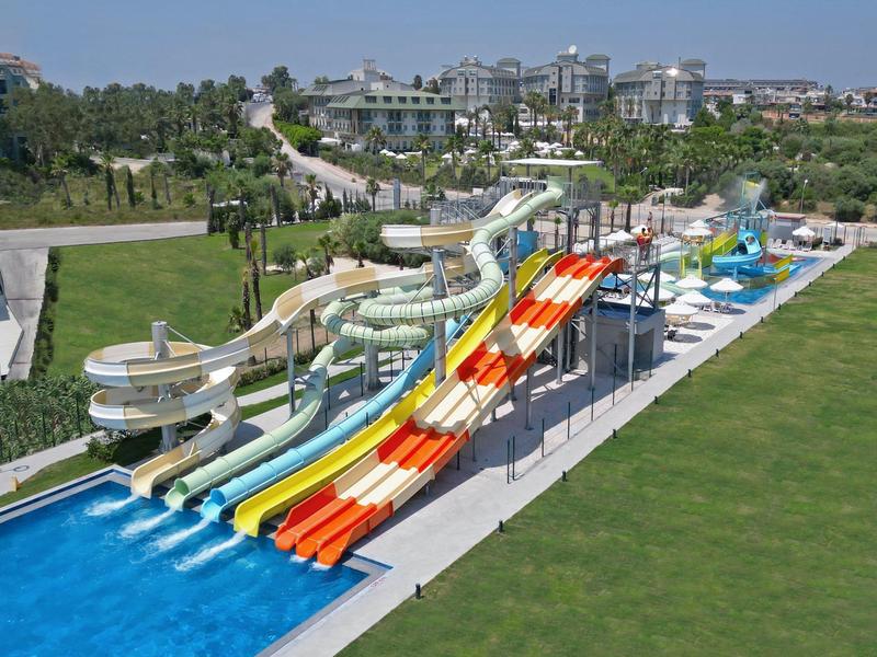 Velký vodní park s několika barevnými skluzavkami a bazénem za slunečného dne