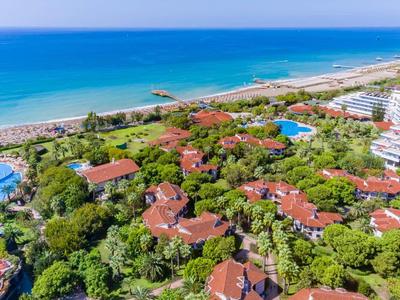 Luxuriöse Hotelanlage mit Pools, roten Dächern, dichter Vegetation und Blick auf das blaue Meer.