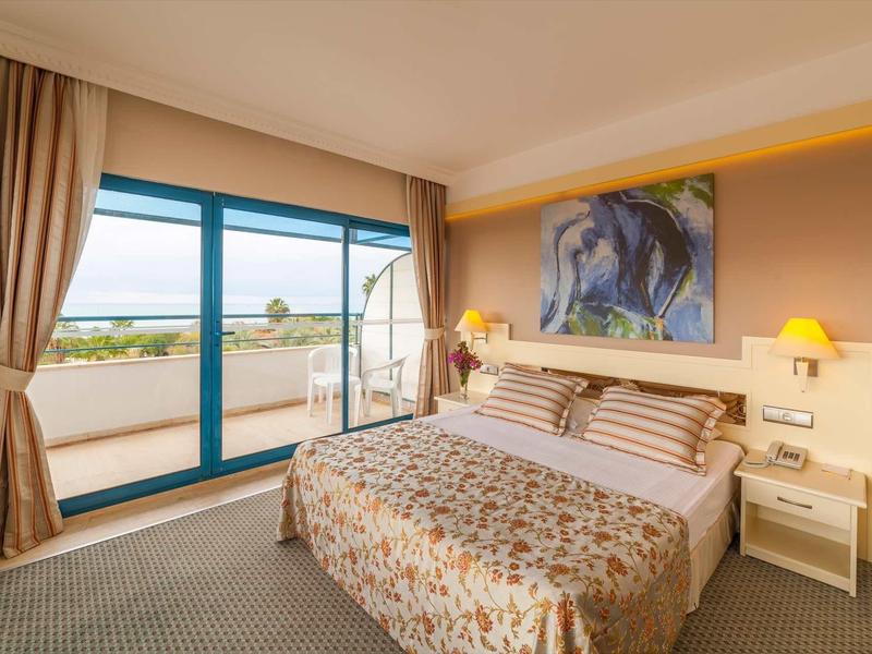 Habitación de hotel acogedora con cama doble, balcón y vista al mar durante el día.